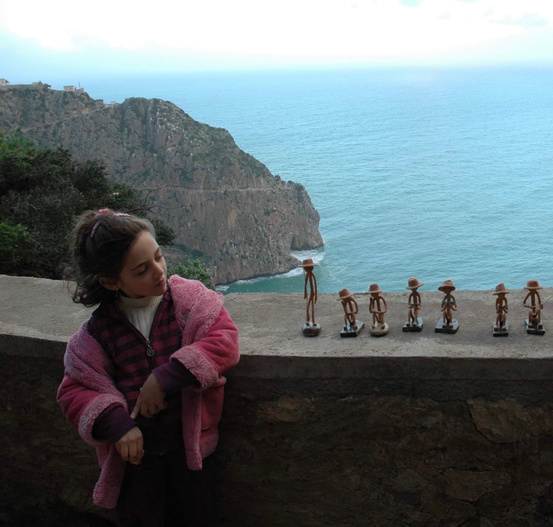 Moi à 4 ans, au Cap Carbon à Béjaïa, absorbée par une rangée de figurines en bois plutôt que par le paysage